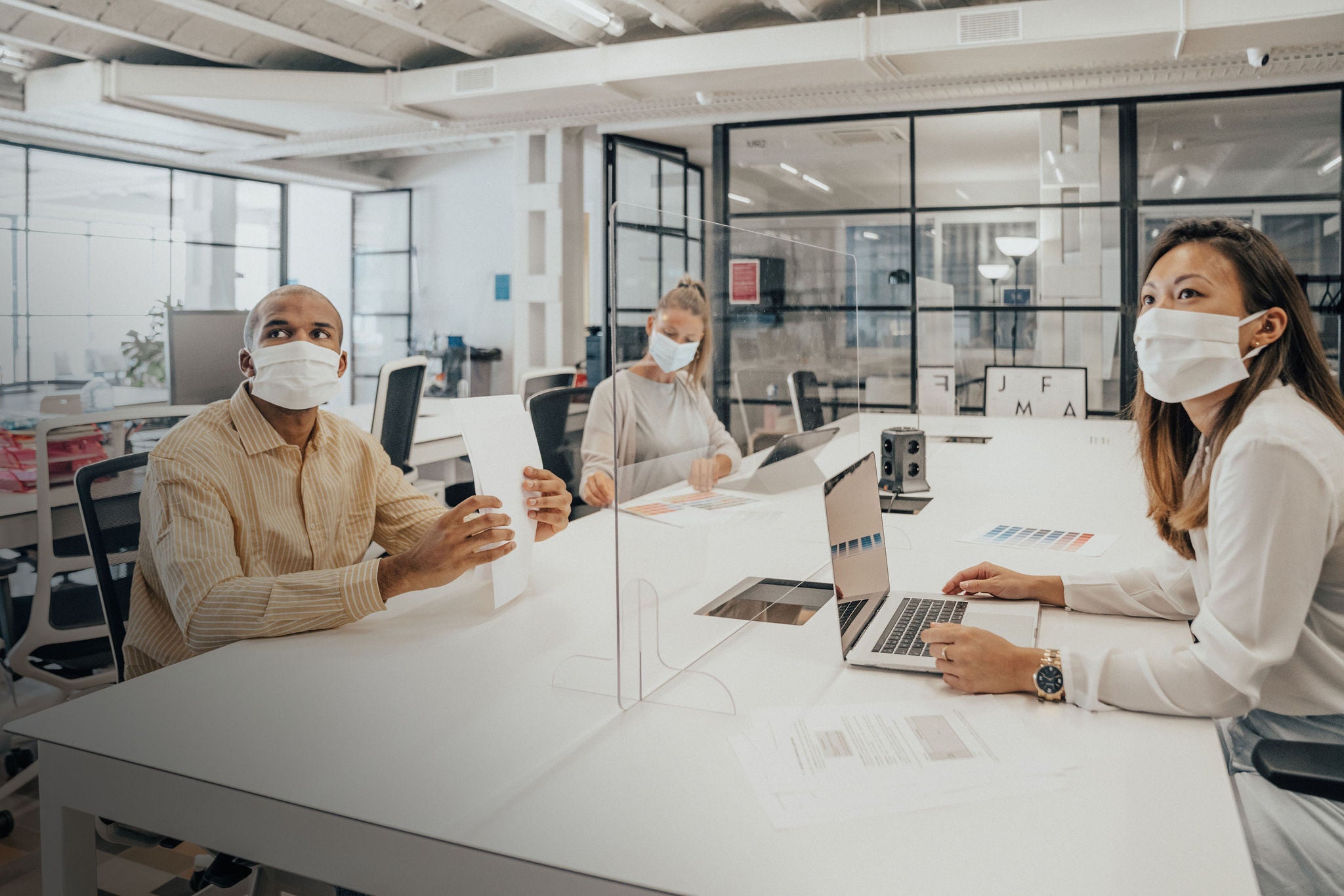 Businesspeople working at office with glass partition dividing them